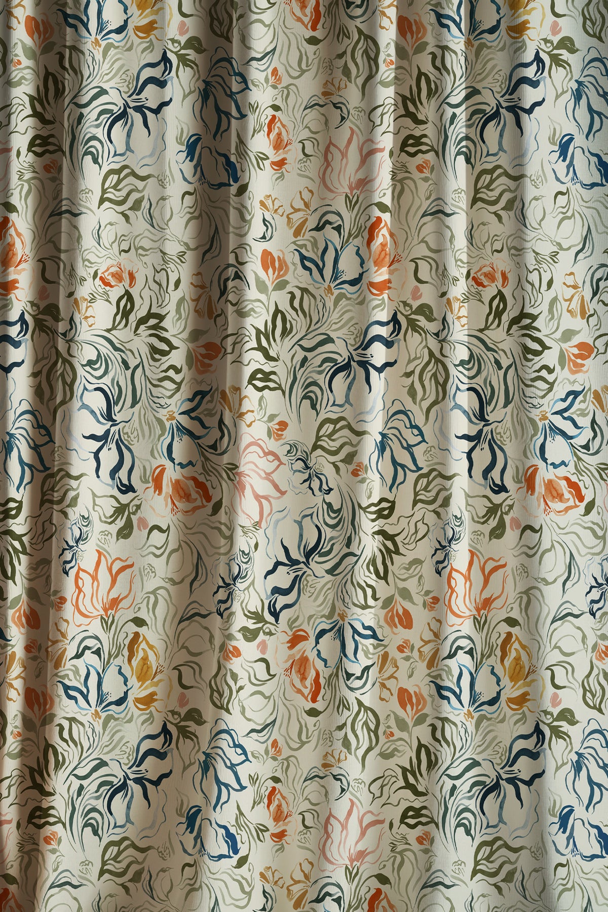 A close-up of a curtain or fabric panel with an all-over floral and leafy pattern on a light beige background, featuring blue, green, and orange botanical motifs.