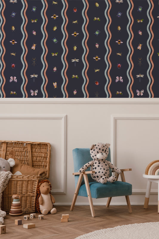 A styled children's room corner showing a navy wallpaper with vertical wavy stripes and small colorful insect motifs above a teal armchair with a spotted teddy bear, plus a wicker basket and toys on a wood floor.