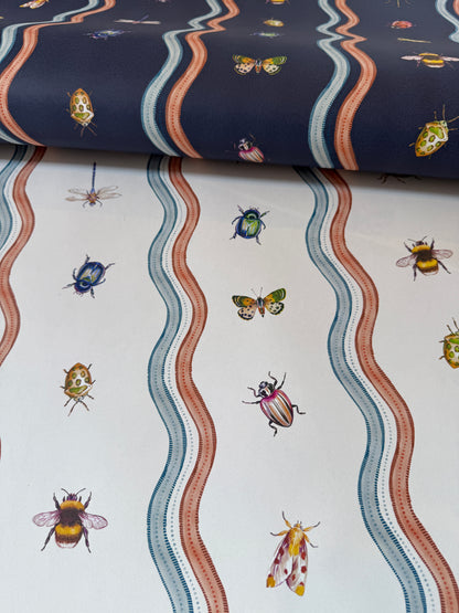 A close-up of patterned fabric or wallpaper showing two sections: one navy blue with wavy coral, cream, and blue stripes and small insects, and one white with matching wavy stripes and illustrated bugs including bees, butterflies, beetles, and moths.