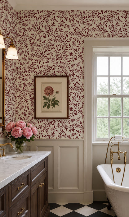 A classic vintage-style bathroom interior featuring a dark red and cream floral leaf patterned wallpaper, white wainscoting, a dark wood vanity with gold hardware, a white freestanding tub with gold fixtures, and a black-and-white checkered floor.