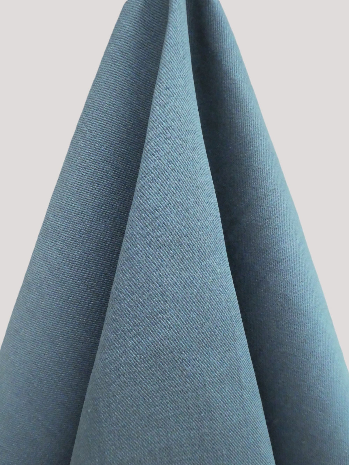 Close-up of blue fabric with a textured pattern on a light gray background