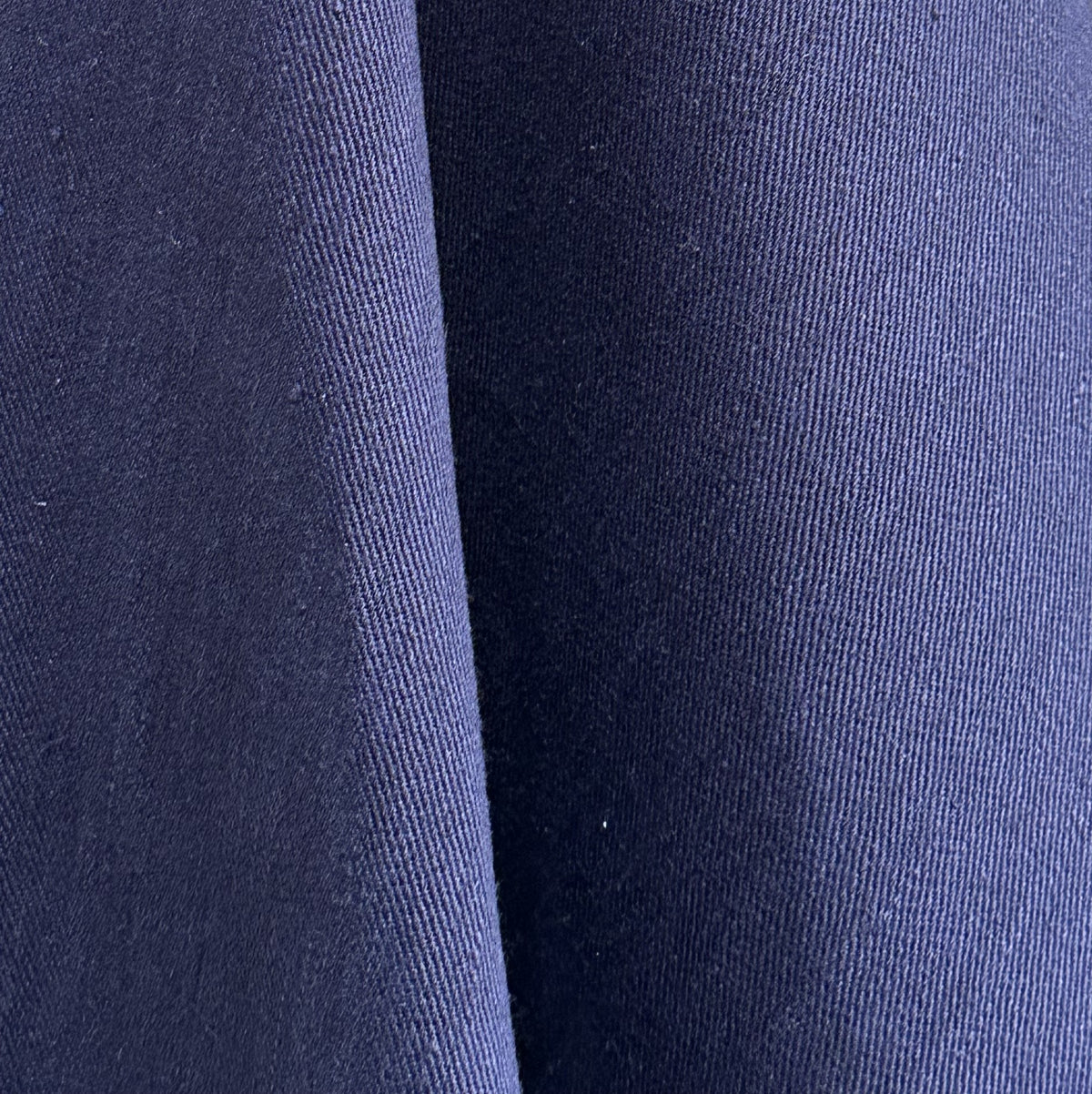 A close-up of dark navy blue fabric with a fine ribbed texture and soft folds.