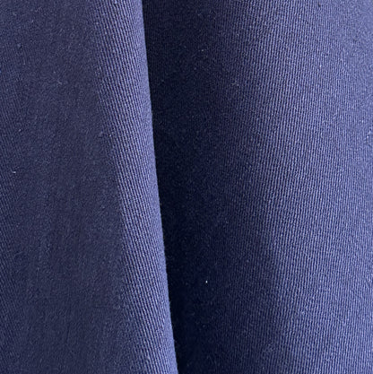 A close-up of dark navy blue fabric with a fine ribbed texture and soft folds.