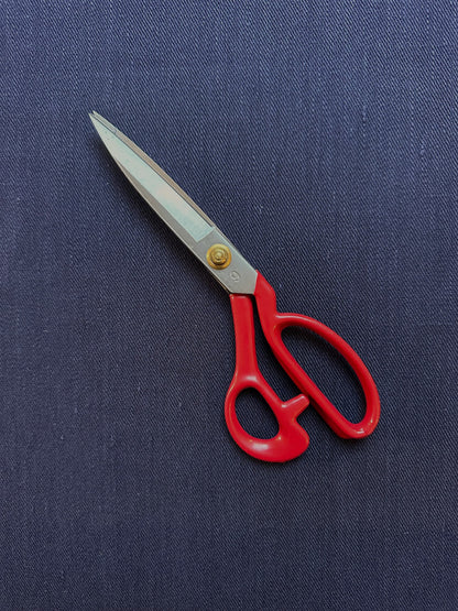 Red-handled scissors on a blue fabric background
