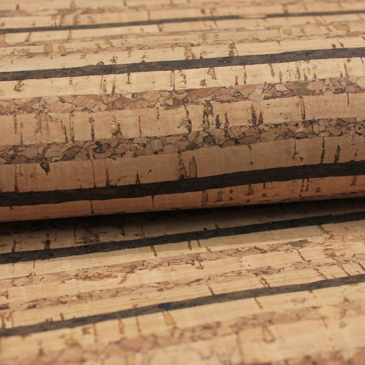 A close-up of a cork material sample showing natural cork texture with horizontal dark brown to black bands on a tan background.