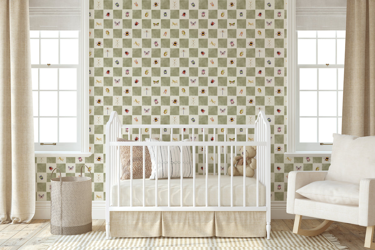 A styled nursery room featuring a green and white checkered wallpaper with small butterfly and floral motifs. A white wooden crib is positioned in front of the wall, flanked by beige curtains, a woven basket, and a white rocking chair.