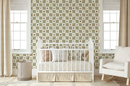 A styled nursery room featuring a green and white checkered wallpaper with small butterfly and floral motifs. A white wooden crib is positioned in front of the wall, flanked by beige curtains, a woven basket, and a white rocking chair.